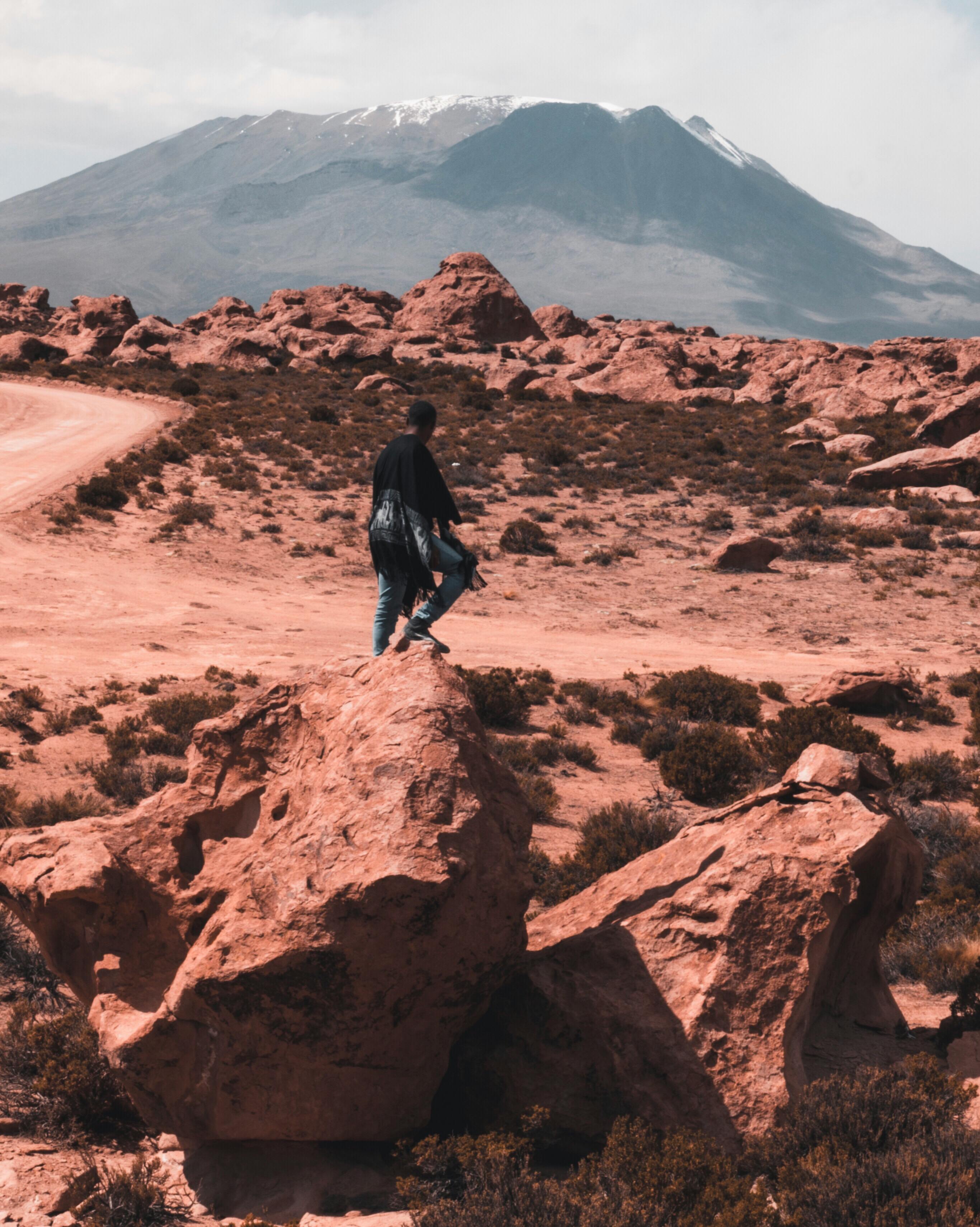 photo of man standing on boulder