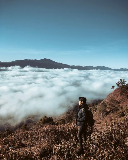 Free Man hiking with a backpack on a mountain in Sagada, Philippines, under a clear sky. Stock Photo