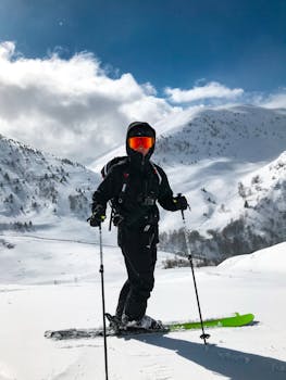 Energetic skier in black gear enjoying snowy slopes under blue sky and sunlight