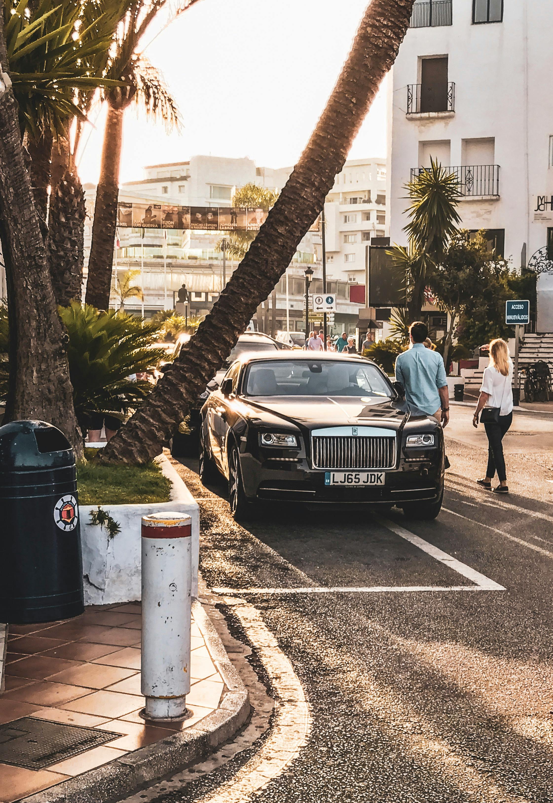 High-end luxury car parked on a vibrant urban street during golden hour.