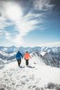 两人在法国韦兹的雪山上徒步旅行，头顶是明亮的冬日天空