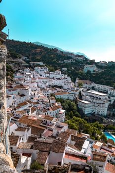 Scenic view of a whitewashed village nestled in the hills of Spain, surrounded by lush greenery.