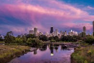 芝加哥天际线映衬着充满活力的日落，倒影静静地躺在池塘里，四周环绕着郁郁葱葱的绿意