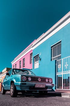 在南非开普敦，一辆经典古董车停在色彩缤纷的房屋旁，展现出充满活力的建筑风貌