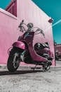 在南非开普敦，一辆鲜艳的粉色滑板车停在彩色墙上