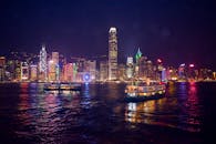 香港迷人的夜色中，明亮的天际线与渡轮的倒影在水面上交相辉映