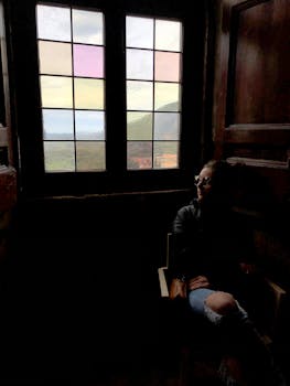 在意大利蒂沃利，一名妇女若有所思地坐在窗前，景色宁静