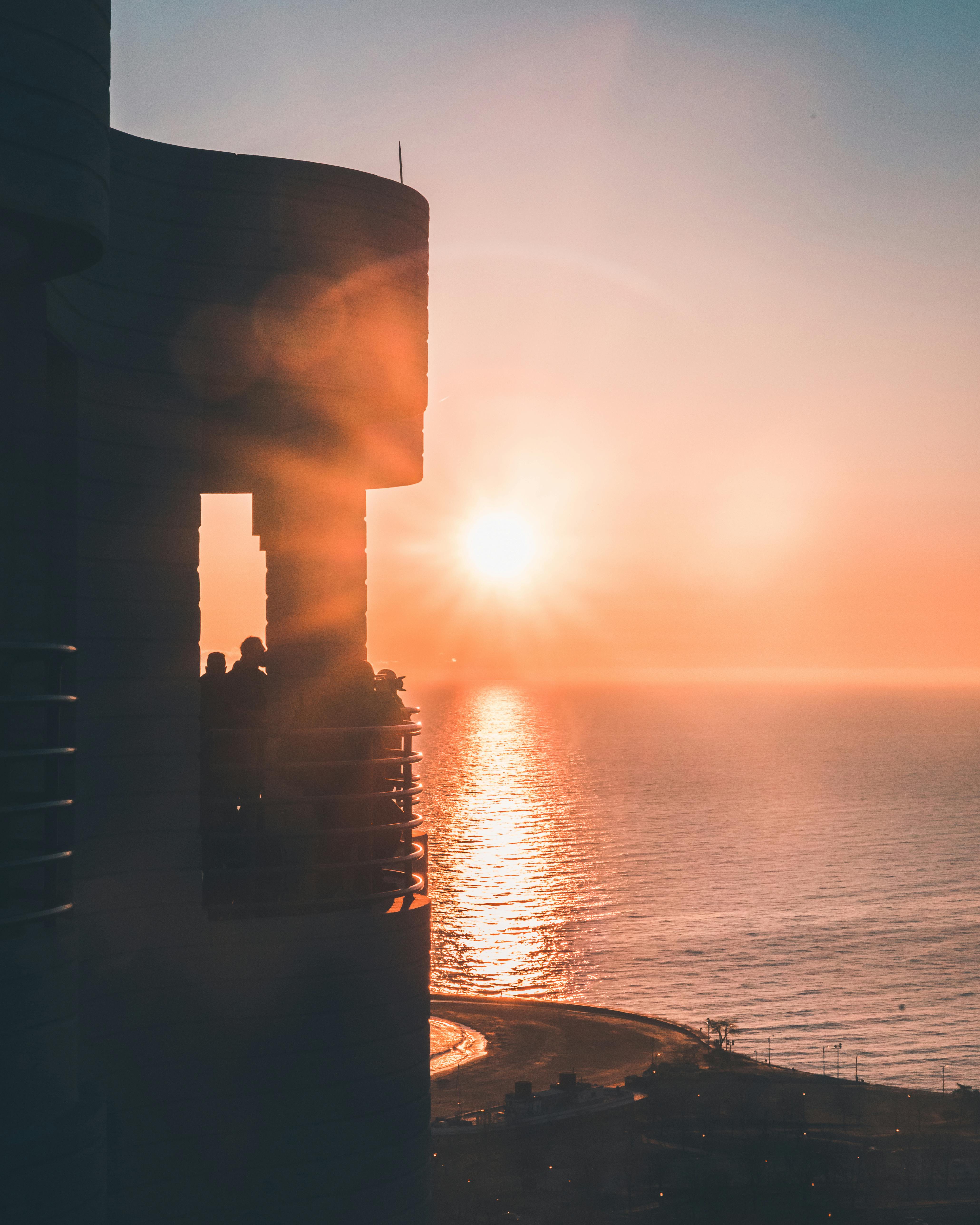 在密歇根湖上空充满活力的芝加哥日落中，阳台上的人们呈现出剪影