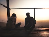 两个朋友在木甲板上欣赏美丽的日出，勾勒出美丽的轮廓