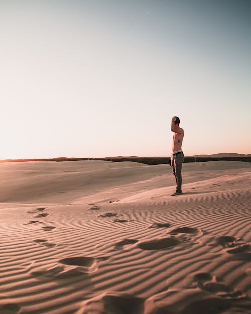 Photo of Topless Man Standing on Desert