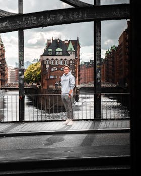 在汉堡的一座桥上，一名年轻人站着，背景是标志性建筑