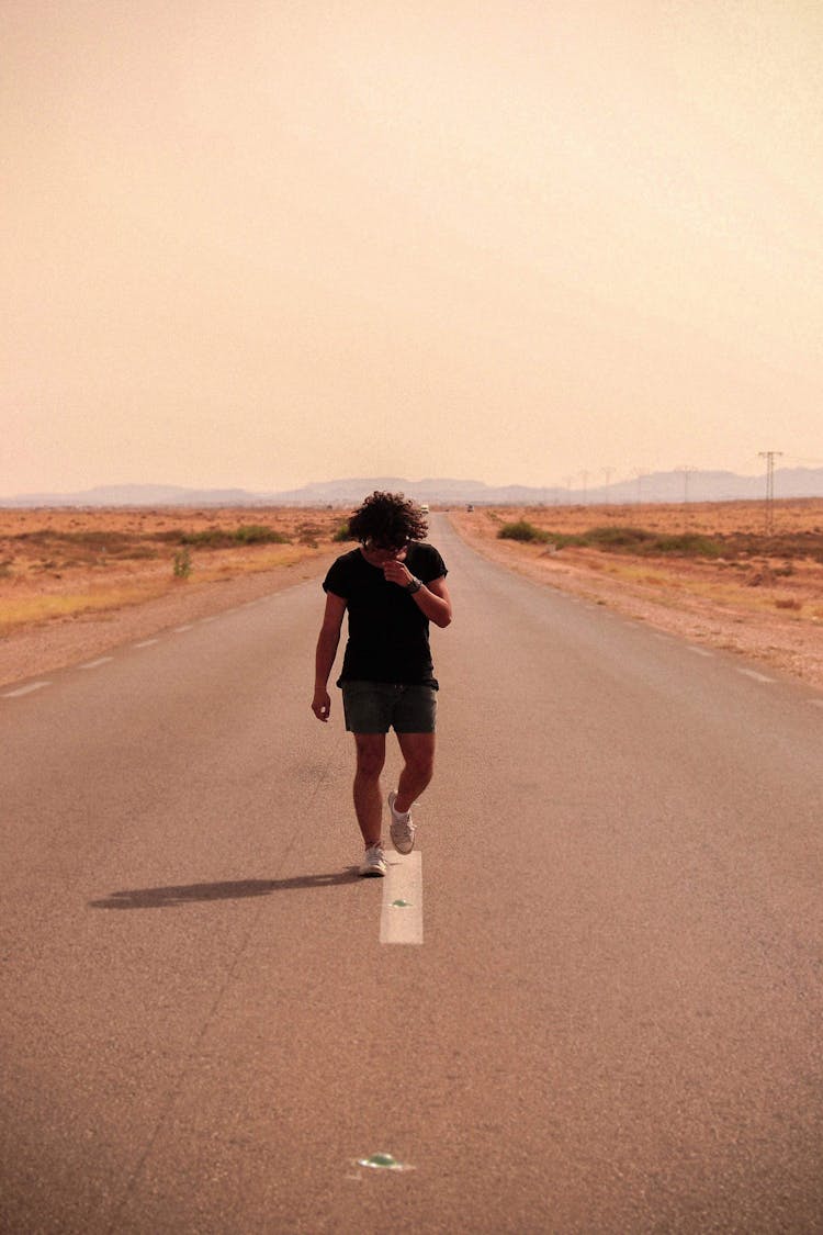 Photo Of Man Looking Down While Walking In The Middle Of The Road