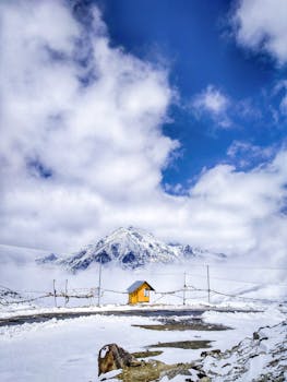 雪云笼罩的宁静山地间，一座黄色小屋静静矗立，非常适合冬季风景爱好者