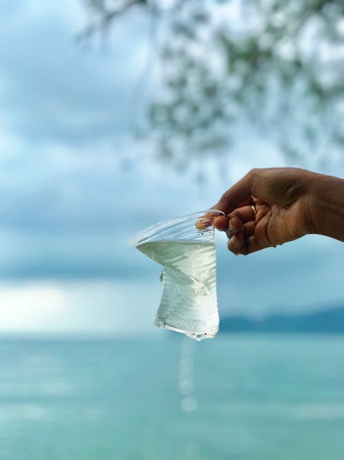 Foto Der Person, Die Plastikbecher Mit Wasser Hält