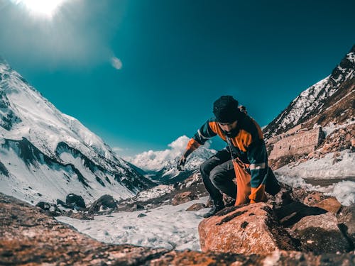 Free Man jumping over a brown rock  on a mountain Stock Photo