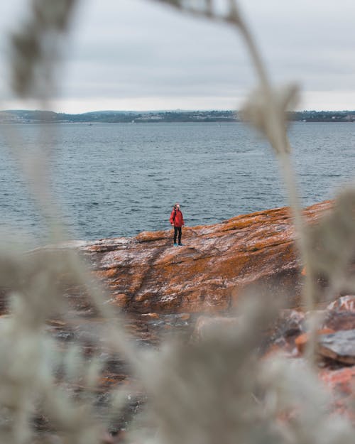 Man Standing on Rock Near Body of Water