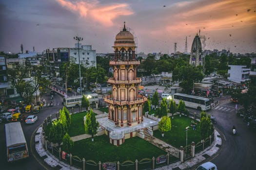 Aerial view of a historic tower in Ahmedabad, India at dusk surrounded by urban cityscape.