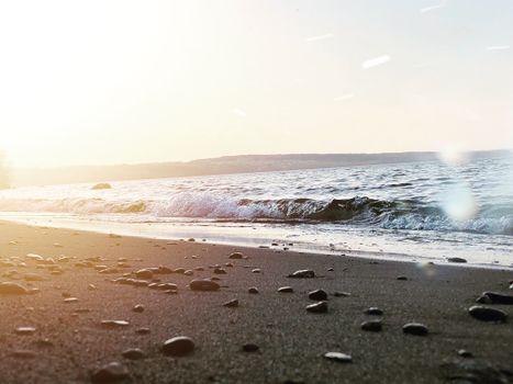Peaceful evening at the beach with gentle waves and a glowing sunset in the background.