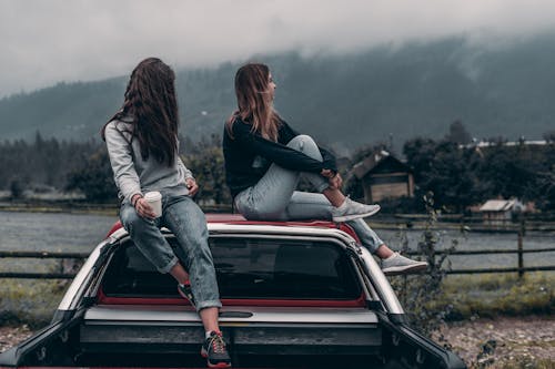 Две женщины, сидящие на крышах автомобилей