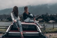 Two Women Sitting on Vehicle Roofs