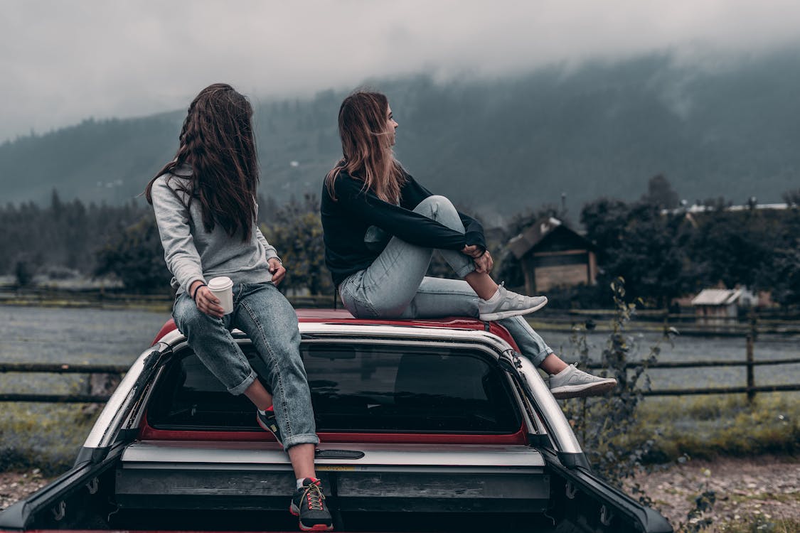 Zwei Frauen Sitzen Auf Fahrzeugdächern