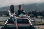 Two Women Sitting on Vehicle Roofs