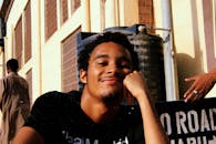 在城市背景下，一个快乐的年轻人在户外微笑着