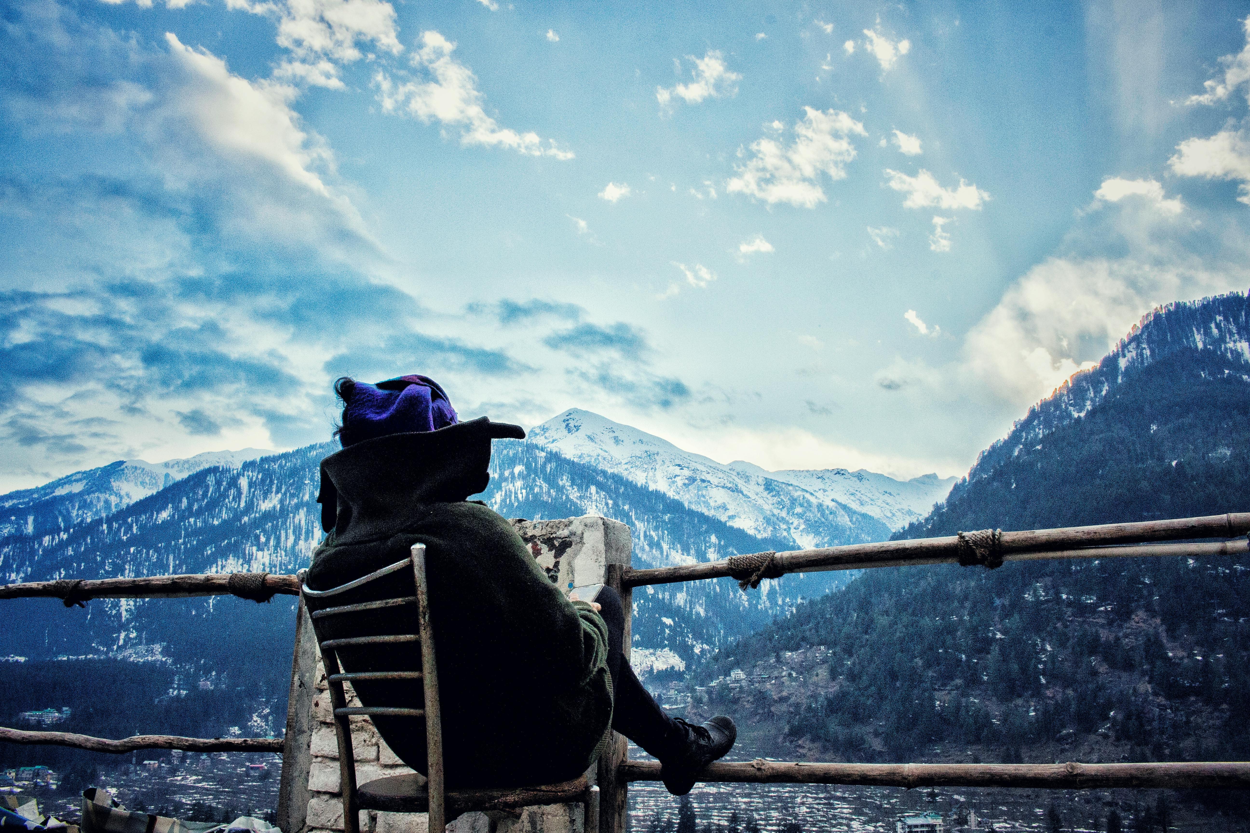 一个身着冬装的人，正欣赏着白雪皑皑的山脉间那份宁静的景色