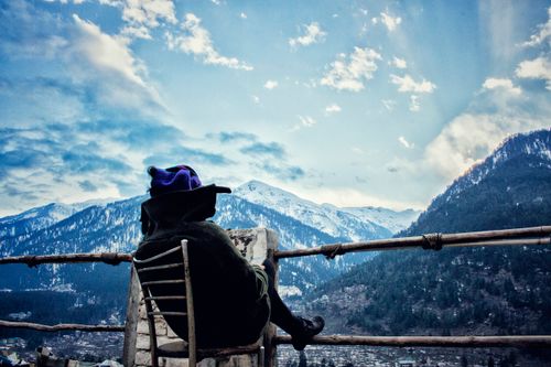 Free A person in winter attire enjoys a serene view of snow-covered mountains. Captivating winter landscape. Stock Photo