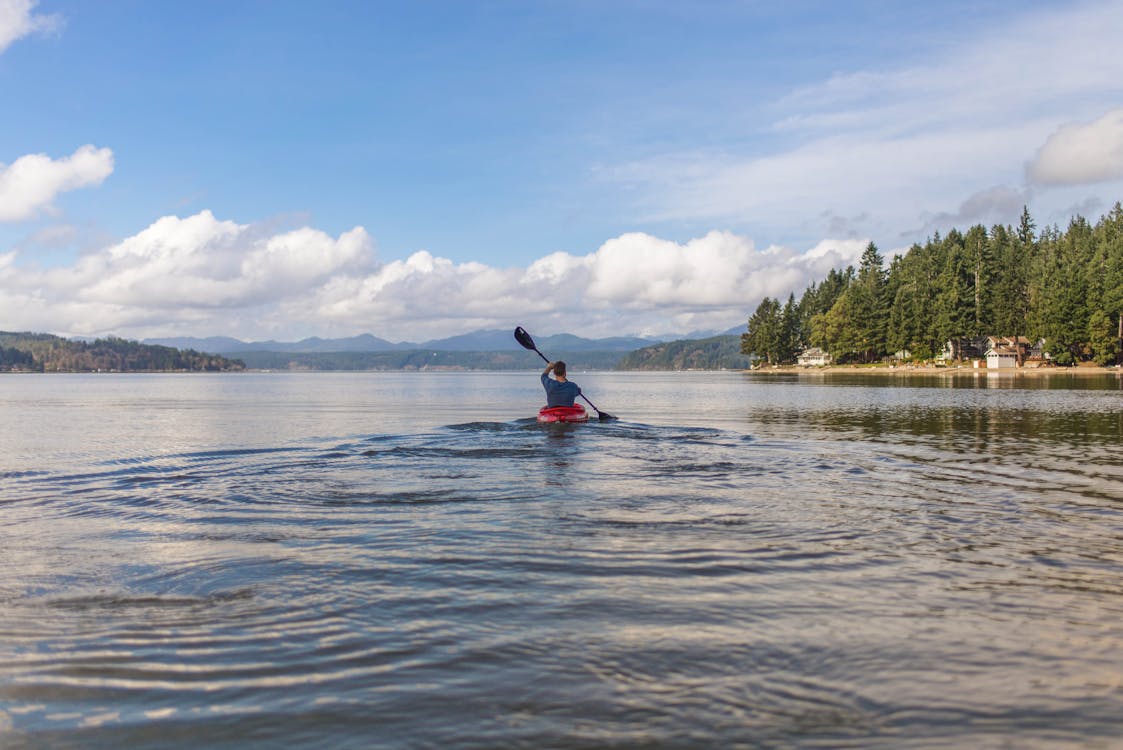 Person on Kayak Under Blue and White Sky