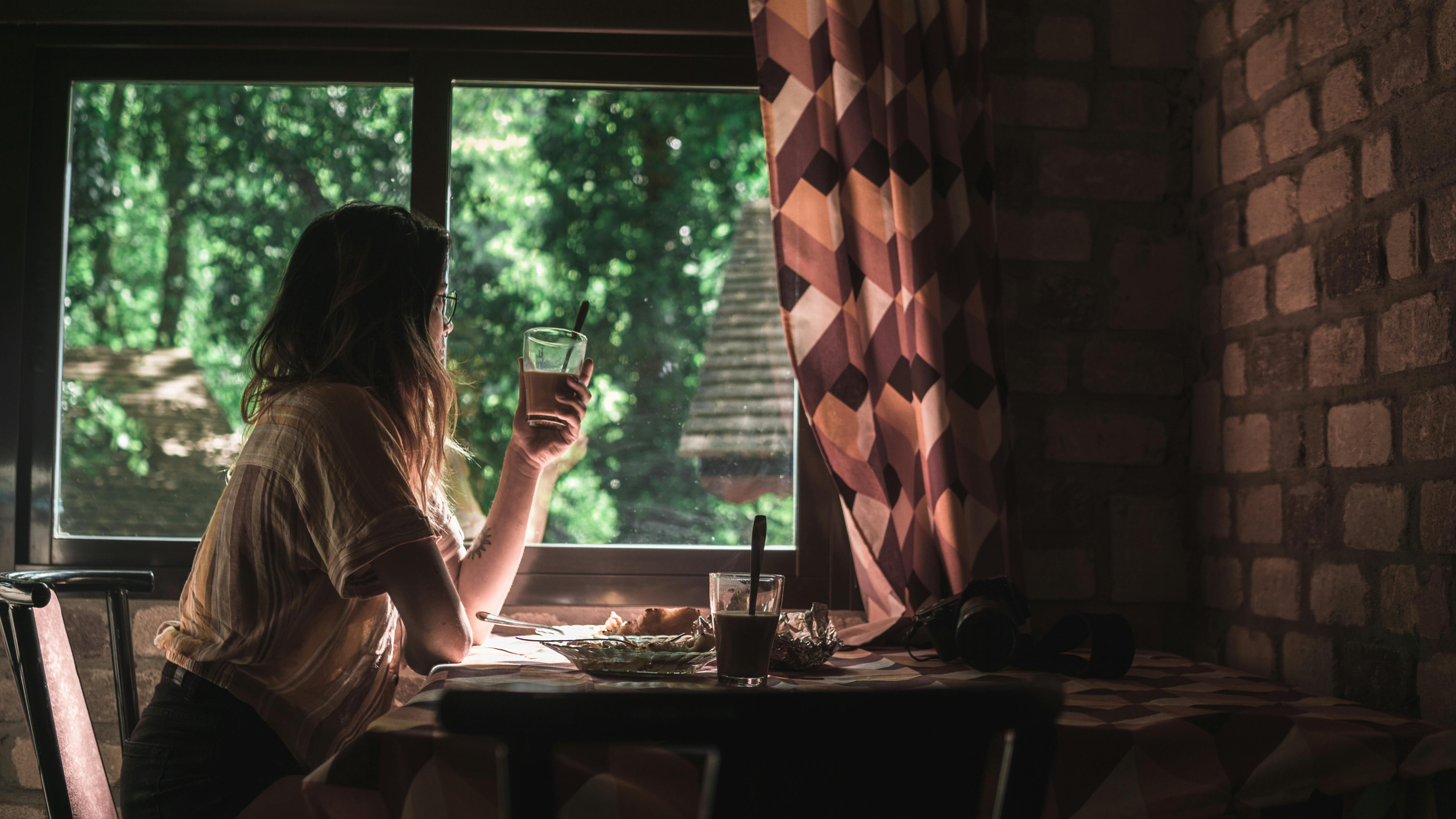 woman sitting on chair holding clear glass cup