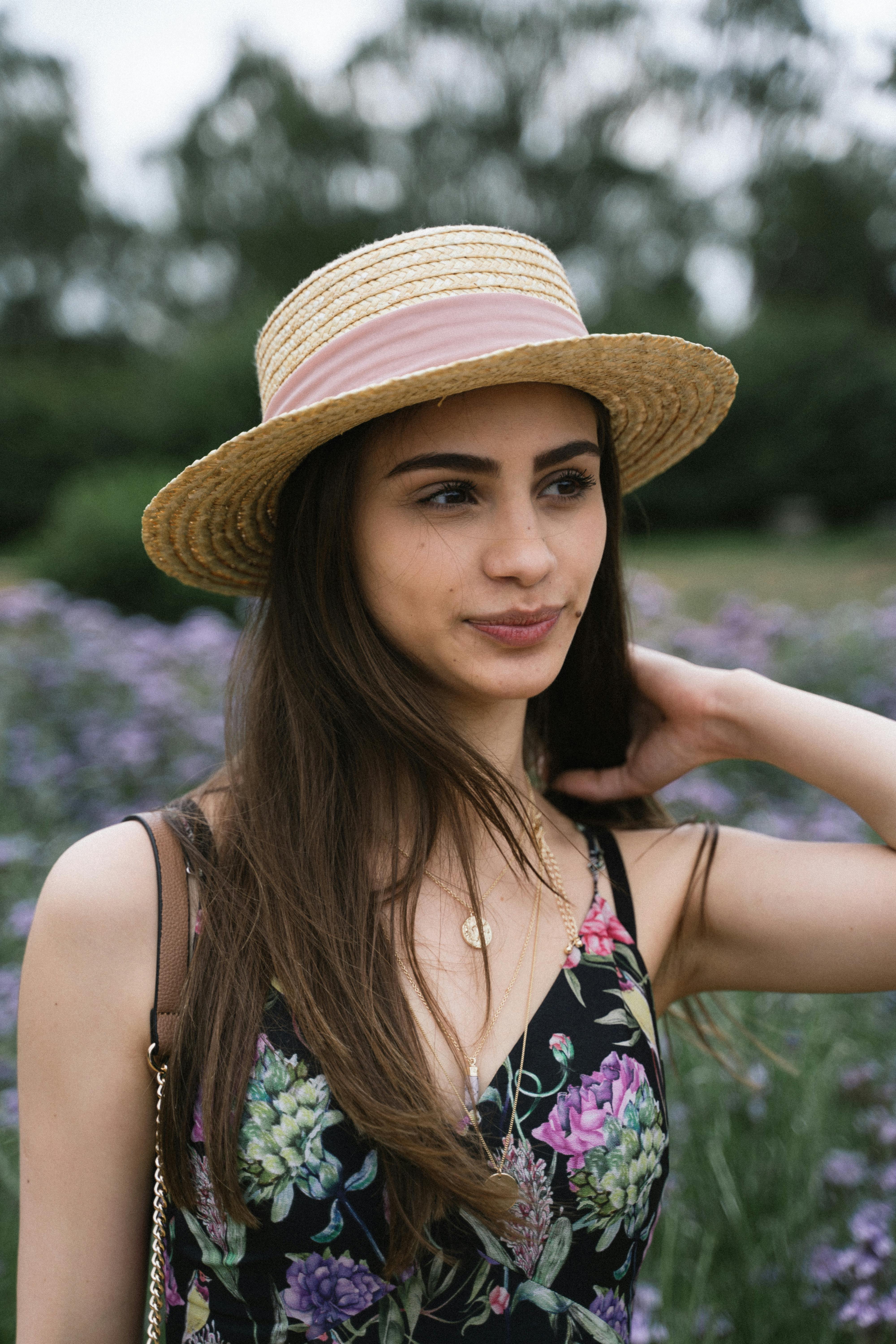 英国剑桥花田中，一位年轻女子身着花裙、头戴太阳帽的肖像