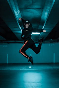 Man in athletic wear performing a dynamic jump in an urban parking garage at night.
