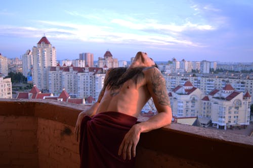 Free Topless Man Leaning on Wall over the Building Stock Photo