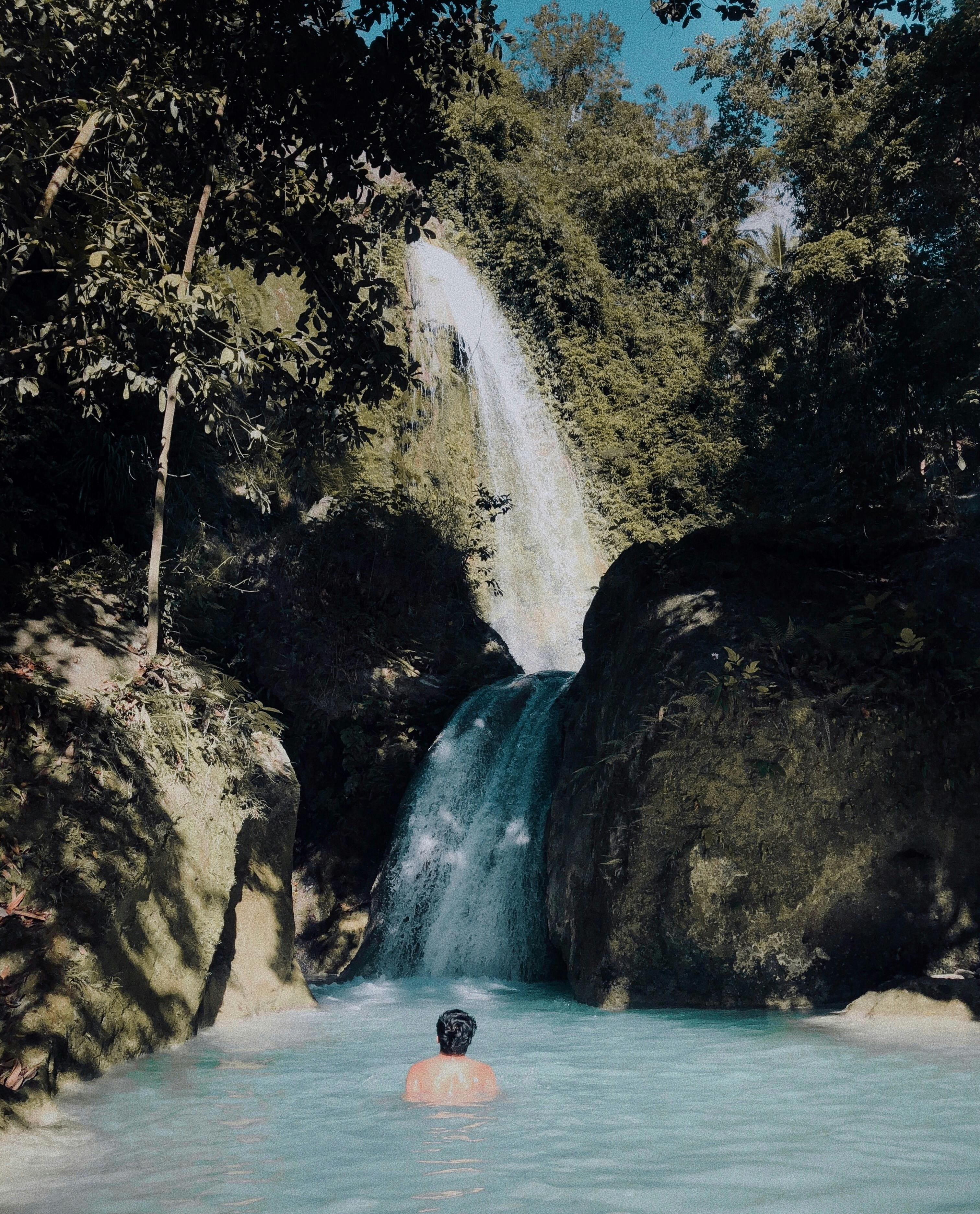 Person Swimming Under Waterfalls · Free Stock Photo
