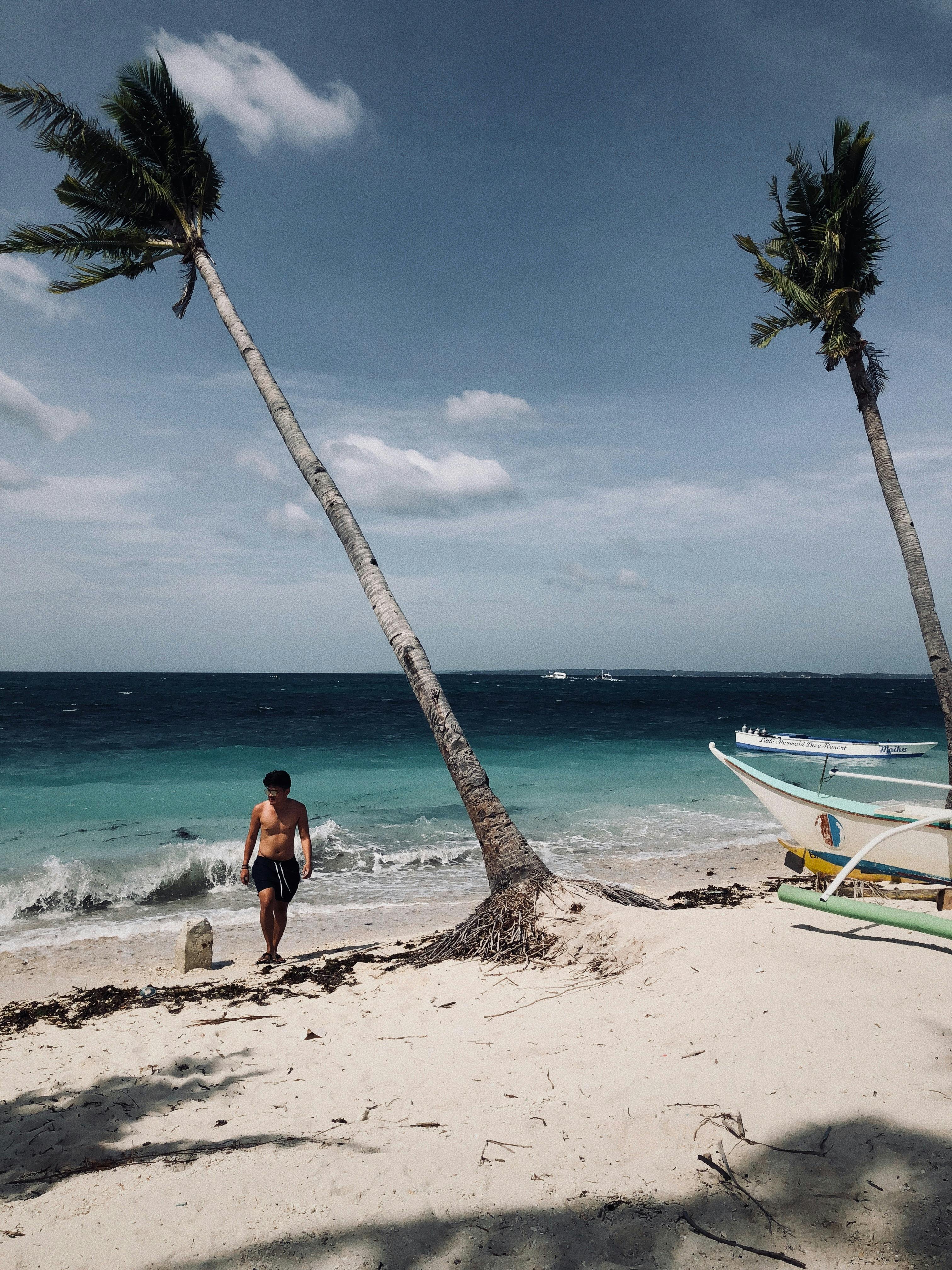 Man in White Shirt and Black Shorts Walking in Beach · Free Stock