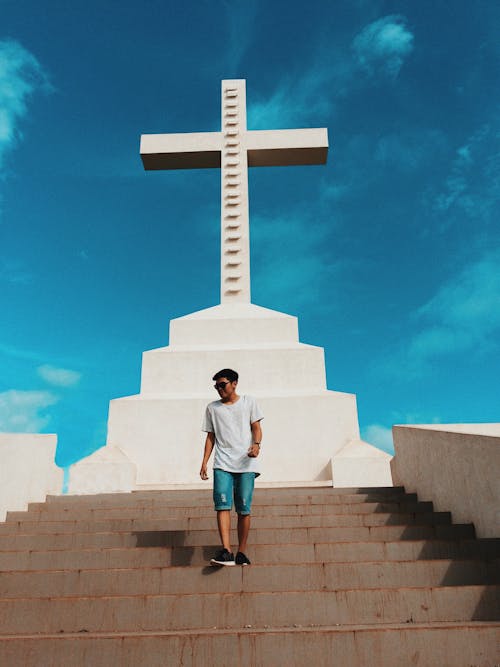 Человек, стоящий на лестнице на фоне статуи Креста