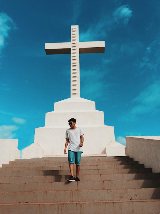 Free Man Standing on Stair Under Cross Statue Background Stock Photo