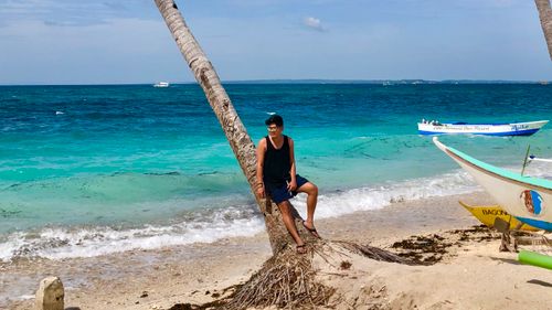 Free A man enjoys a sunny day on a tropical beach with palm trees and ocean views. Stock Photo