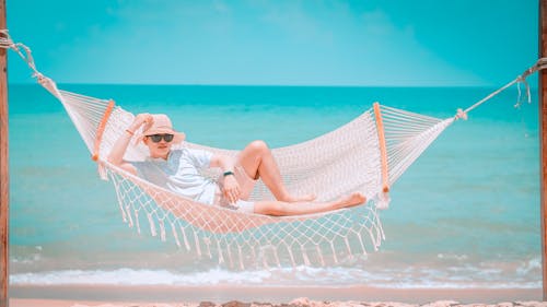 Free Man Lying on White Hammock On Seashore Stock Photo