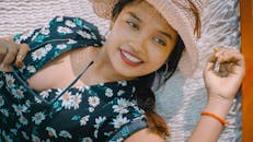 一个穿着花裙的女人微笑着在吊床上享受夏日的放松