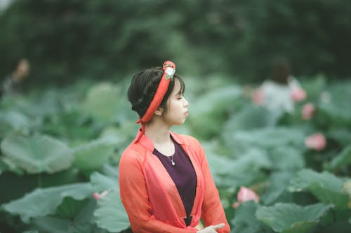 Selective Focus Side View Photo of Woman in Colorful Outfit Posing with Her Eyes Closed Standing in the Middle of Flower Field