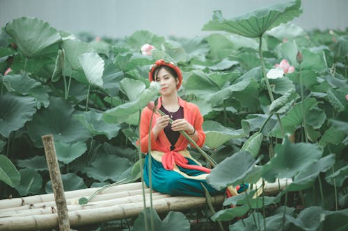 Mujer En Chaqueta Roja Sentada Cerca De Plantas