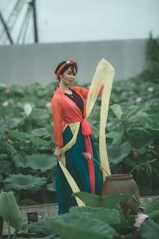 亚洲妇女身着充满活力的服装，站在郁郁葱葱的莲花植物丛中