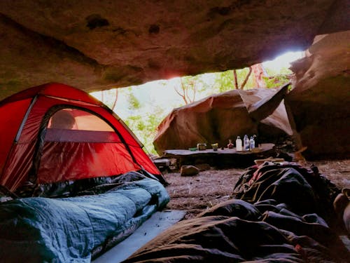 Free Explore the serenity of cave camping with a red tent in a natural setting, capturing relaxation and adventure. Stock Photo