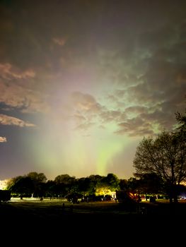 Beautiful aurora borealis illuminating the night sky over a park with trees.