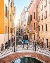 一位时尚人士坐在桥上，俯瞰着环绕历史建筑的威尼斯运河