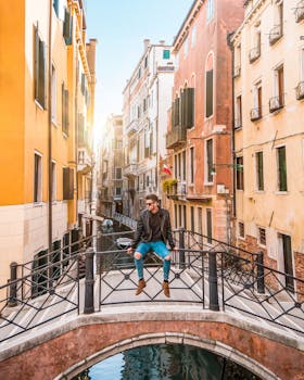 一位时尚人士坐在桥上，俯瞰着环绕历史建筑的威尼斯运河