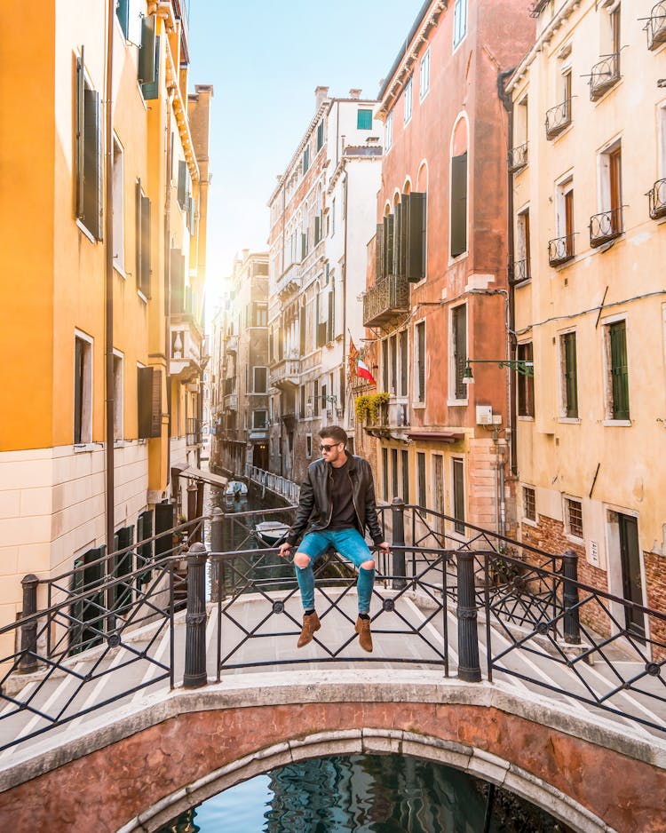 Man Sitting On Bridge Railings