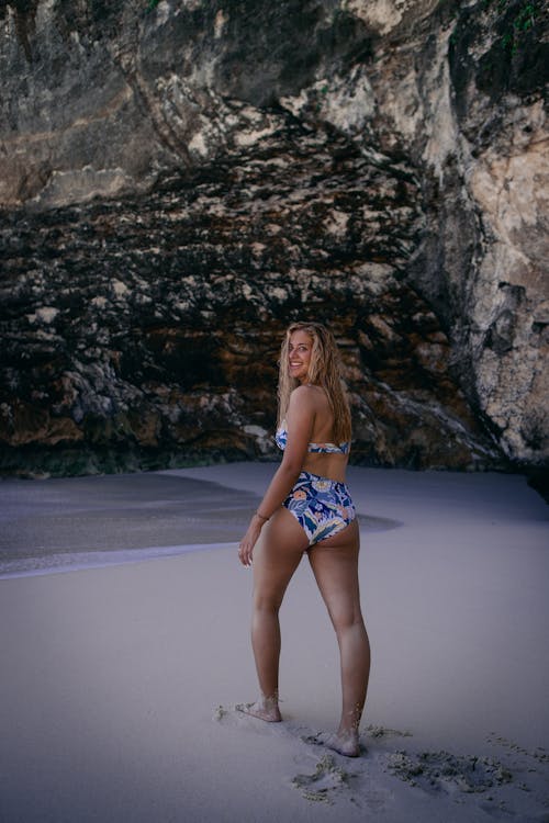 Foto Der Lächelnden Frau Im Blau Weißen Bikini Set, Das Durch Den Zurückblickenden Strand Geht
